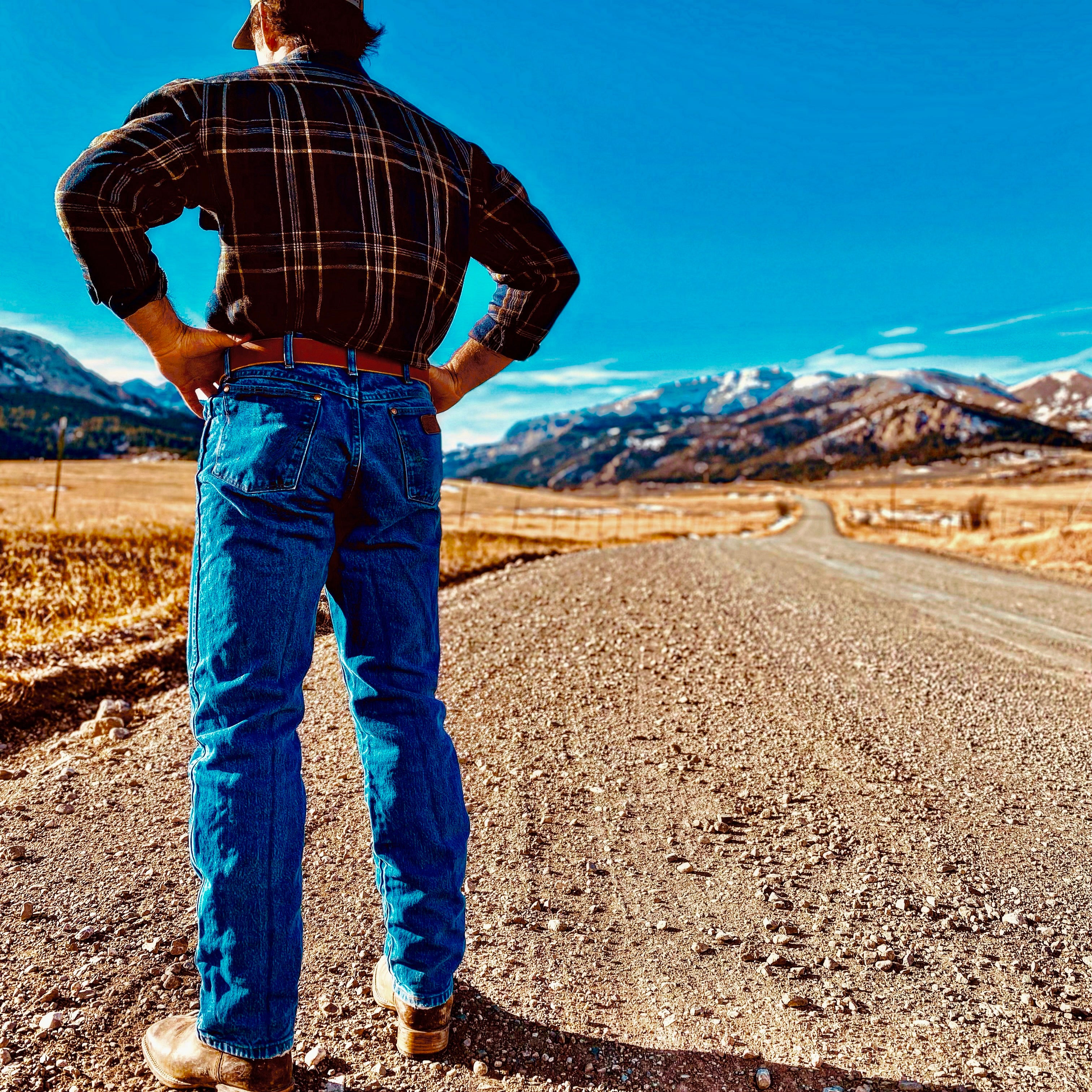 Mack wearing Mack Belt in Montana fields with mountain background, blue jeans outfit